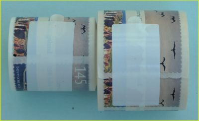 Rollenvergleich Helgolandmarke selbstklebend mit dem Verschlussaufkleber – rechts die echte Marke mit dem größeren Rollendurchmesser, links die falsche Marke die wesentlich enger gerollt ist